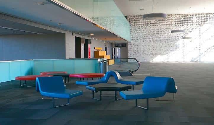Área de descanso moderna con mobiliario azul y rojo en el interior del recinto