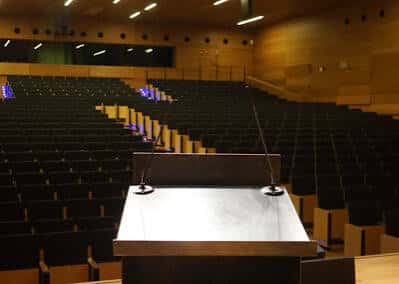 Aula magna o auditorio con gradas y atril listo para conferencias