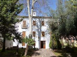 Fachada principal de la Casa de la Dona en Villareal, rodeada de árboles y con jardín