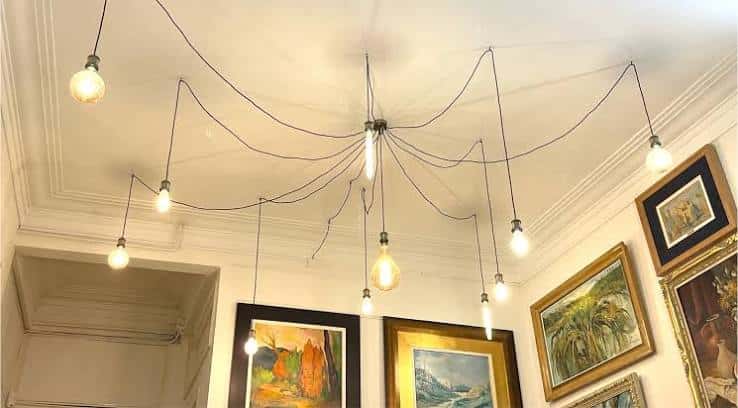 Detalle decorativo del techo con lámparas colgantes y obras de arte enmarcadas