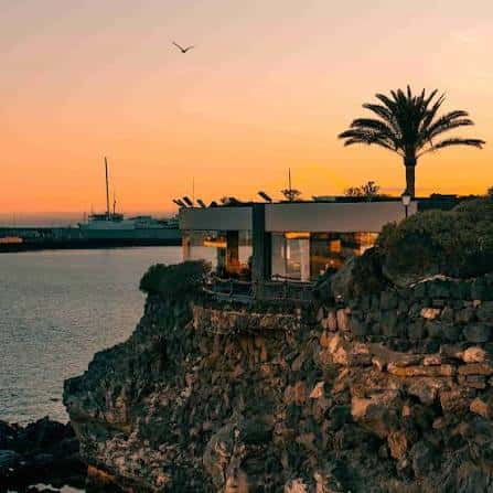 Fachada del Castillo de San José al atardecer, ubicado sobre acantilados junto al puerto