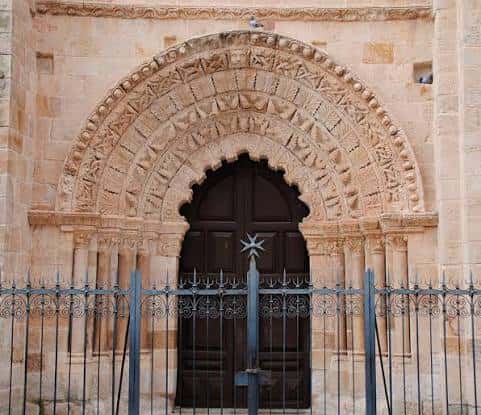 Detalle de la portada románica con arco decorado y puerta de madera