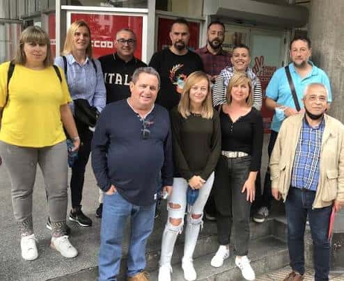Grupo de personas posando frente a la entrada de un local de CCOO