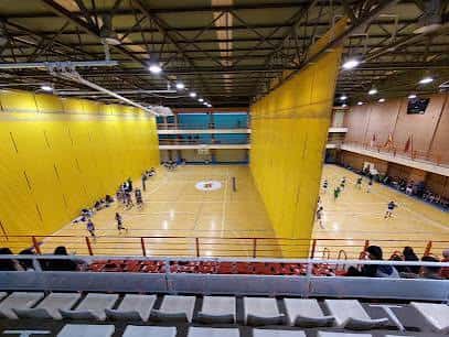 Interior del polideportivo mostrando múltiples pistas deportivas y gradas