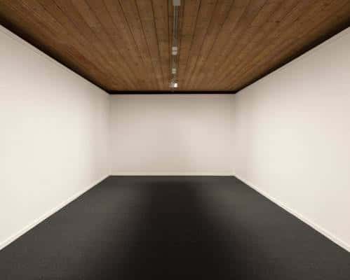Interior de una galería blanca con techo de madera y suelo negro