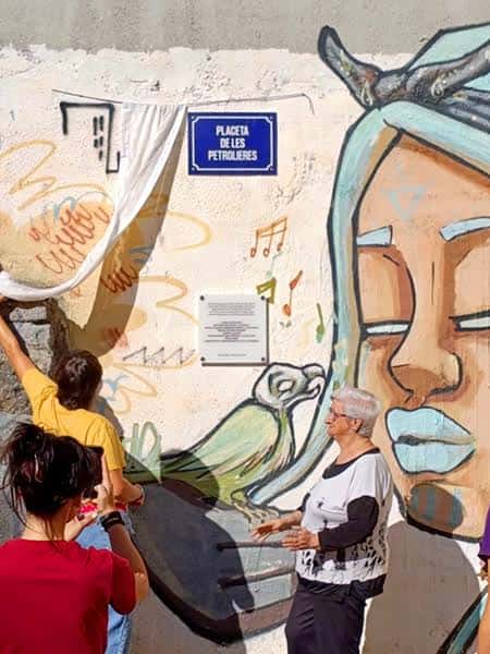Vista de la placeta con murales artísticos y personas interactuando