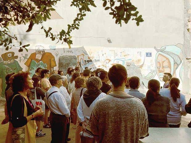 Grupo de personas reunidas frente a los murales en la placeta