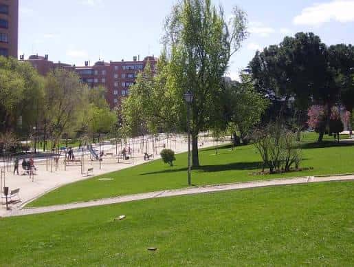 Área recreativa del parque con niños jugando y amplias zonas de césped