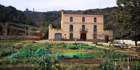 Fachada principal de la Masía Can Soler rodeada de parcelas cultivadas