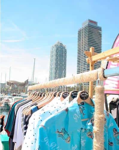 Mercado al aire libre con ropa expuesta y rascacielos de fondo