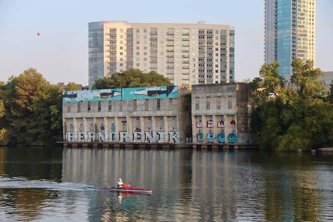 Edificio histórico junto al río con un kayakista pasando frente a él
