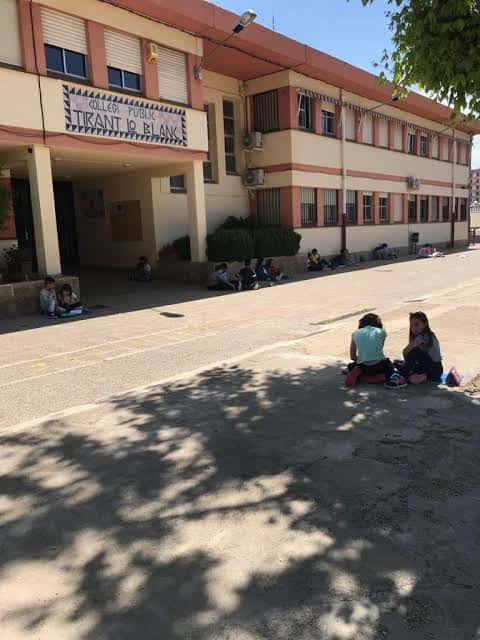 Patio del colegio con alumnos descansando bajo sombra