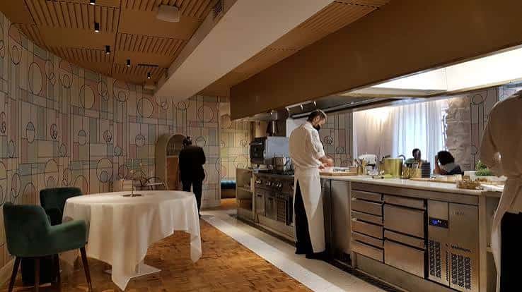 Interior del restaurante LÚ Cocina y Alma mostrando la cocina abierta y una mesa con mantel blanco