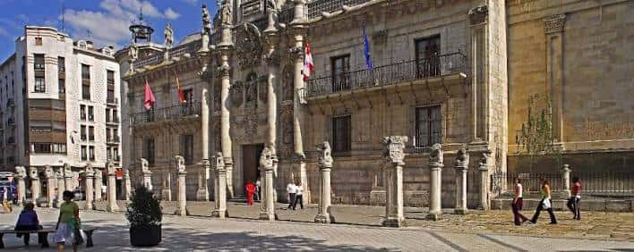 Fachada principal de la Universidad de Valladolid con columnas y esculturas en plaza soleada