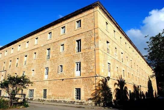 Fachada principal del edificio con mampostería y ventanas simétricas bajo cielo azul