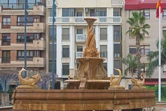 Fuente ornamental central en la Plaza de Colón con edificios residenciales al fondo