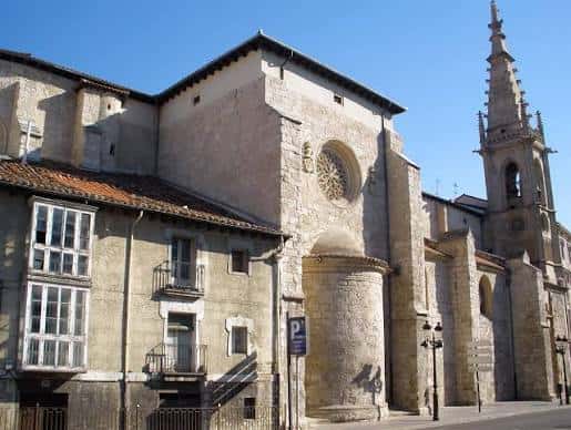 Fachada lateral de la iglesia con rosetón y torre campanario bajo cielo azul