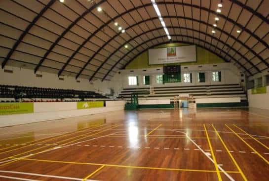 Vista interior del pabellón deportivo con pista de madera y gradas