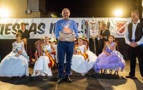 Ceremonia con niños vestidos formalmente y un hombre recibiendo un premio