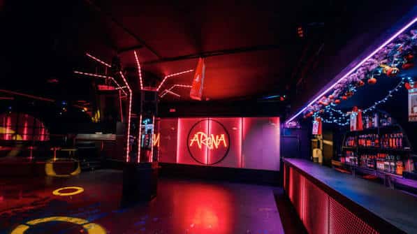 Interior del club Arena Xperience con barra y luces de neón