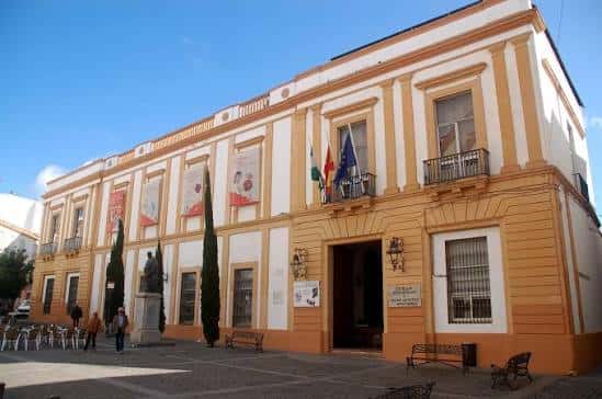 Vista exterior del edificio escolar con banderas y carteles en fachada