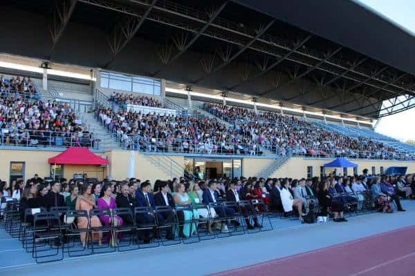 Ceremonia de graduación en el interior del estadio con asistentes sentados en gradas y pista de atletismo
