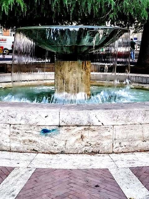 Fuente central del parque con agua cayendo en cascada desde una estructura metálica