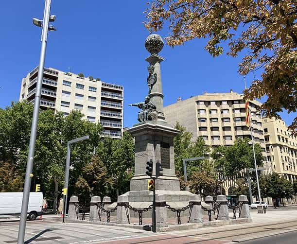 Detalle del monumento a los Sitios de Zaragoza en la plaza, rodeado de edificios modernos