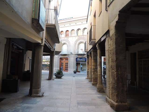 Pasaje cubierto con columnas de piedra que da acceso a la plaza