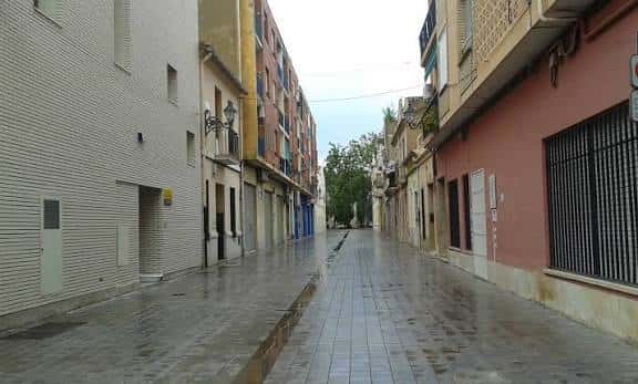 Calle empedrada de Campanar con edificios tradicionales y farolas antiguas