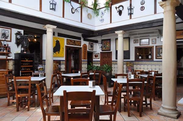 Sala principal de la taberna con mesas dispuestas para comensales y decoración tradicional