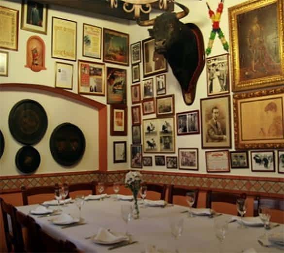Sala privada o comedor decorado con trofeo de toro, cuadros y mesa puesta para evento