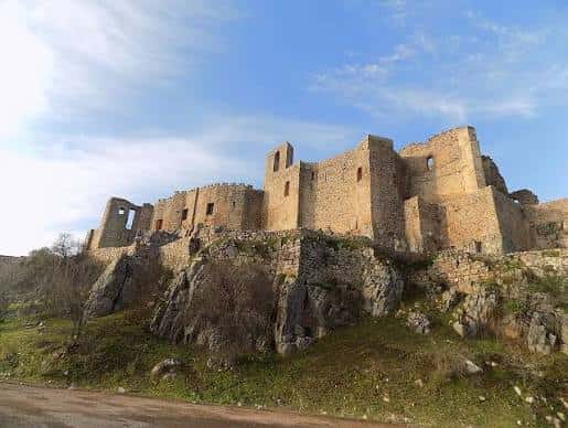 Fachada principal del castillo con muros de piedra y cielo azul
