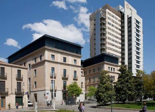 Vista exterior del complejo hospitalario con edificios antiguos y modernos bajo un cielo azul