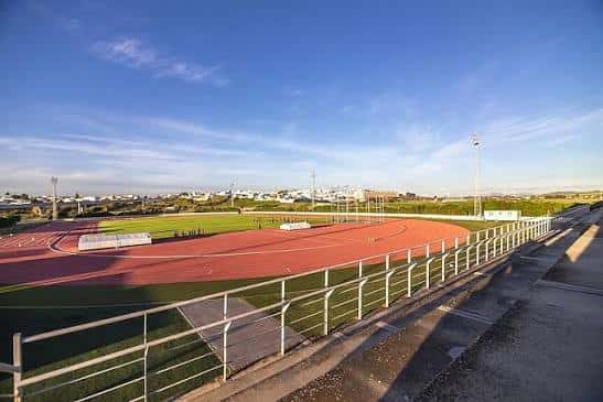 Vista panorámica del estadio con pista de atletismo y gradas bajo cielo despejado