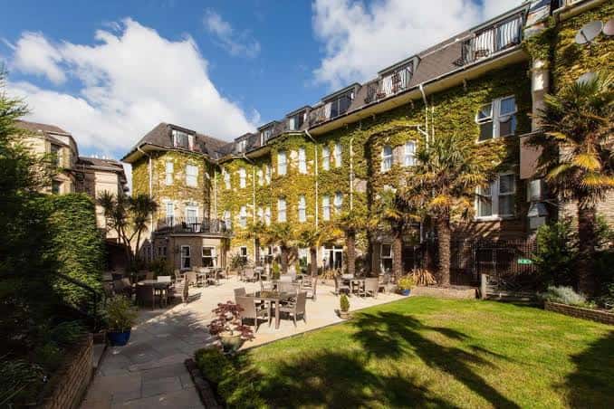 Jardín exterior del hotel con mesas para eventos al aire libre y palmeras