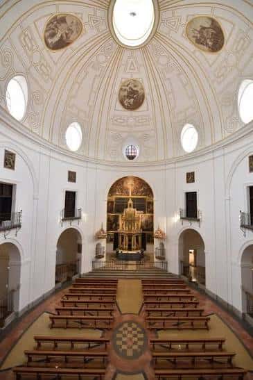 Vista interior de la iglesia con cúpula decorada y altar principal