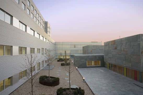 Patio interior del complejo hospitalario con jardines minimalistas y edificios conectados