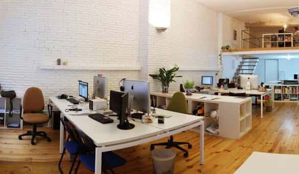 Espacio de coworking con escritorios modernos y paredes de ladrillo blanco