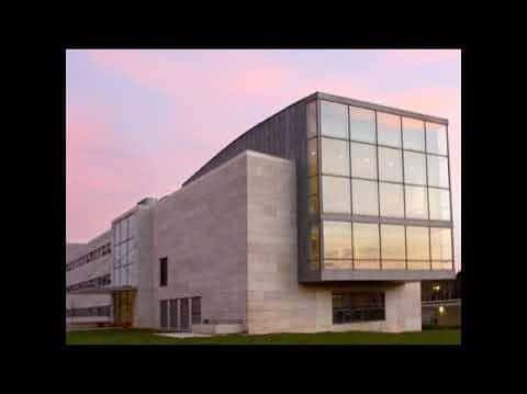 Fachada moderna del edificio con grandes ventanales y cielo rosado