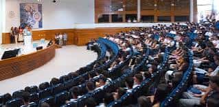 Interior del auditorio curvo con butacas azules y público asistiendo a un evento