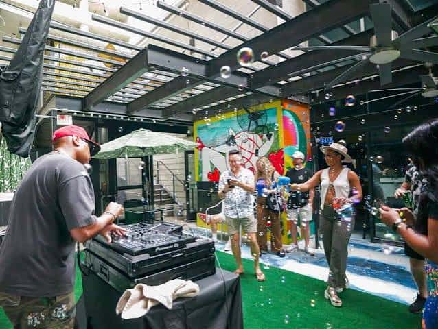 DJ tocando música en el patio con burbujas y gente celebrando