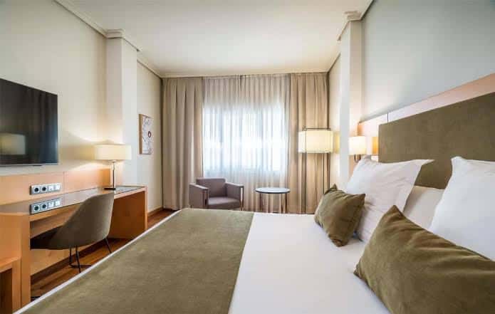 Habitación doble moderna con cama king-size, escritorio y ventana con cortinas