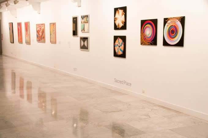 Interior de sala de exposiciones con suelo de mármol y obras de arte abstracto en las paredes