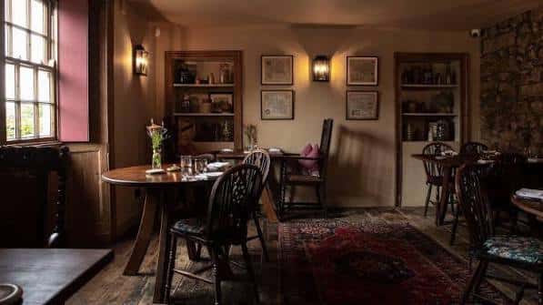 Sala de comedor rústica con mesas de madera, alfombras y decoración tradicional