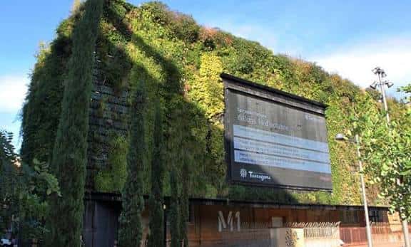 Fachada exterior de Espai Tabacalera con jardín vertical y cartel informativo