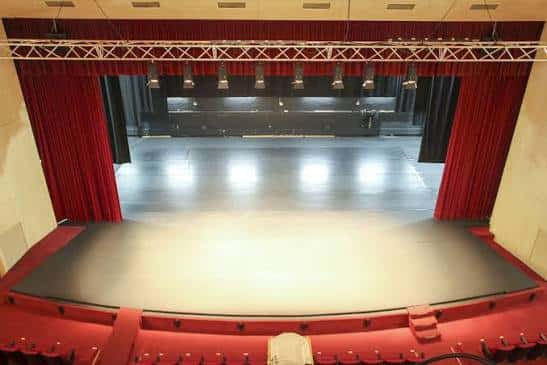 Vista panorámica del interior del auditorio mostrando el escenario y las butacas rojas