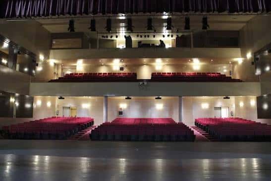 Interior del auditorio con múltiples niveles de asientos y sistema de iluminación profesional