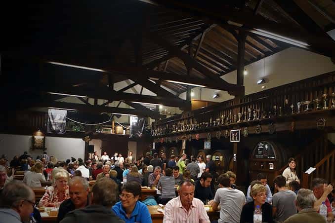 Interior de la Sidrería Ola con techo de vigas de madera y público disfrutando del ambiente