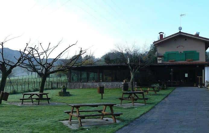 Terraza al aire libre de Borda Txiki con mesas de madera y vistas a la campiña